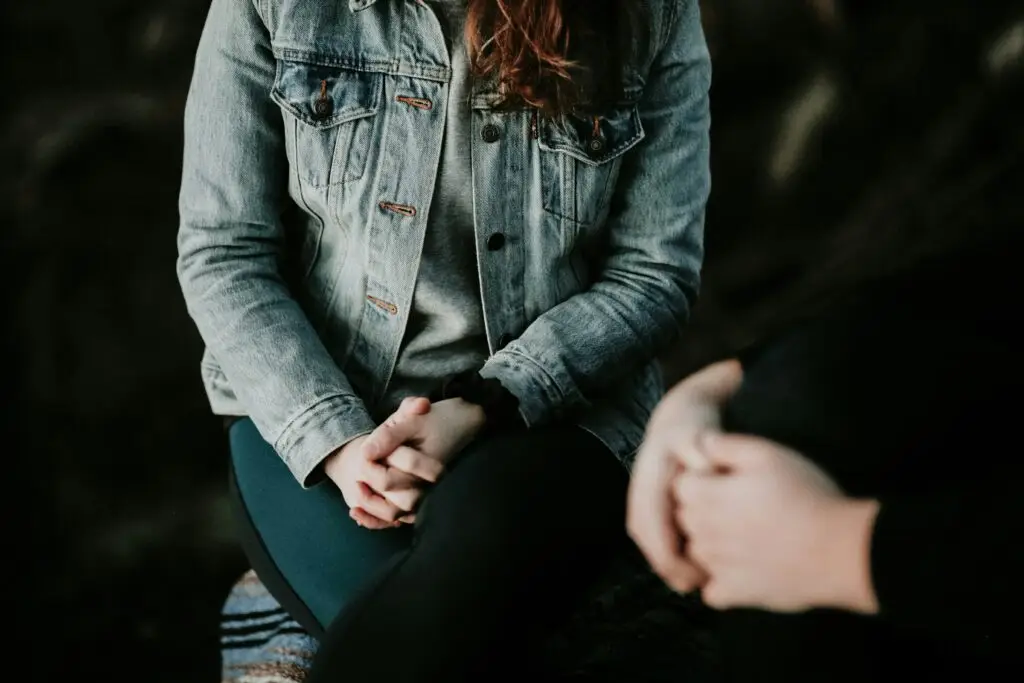 Two people holding hands during a supportive counseling conversation outdoors.